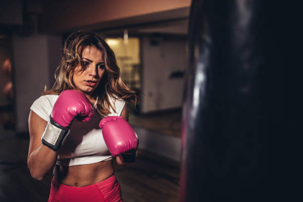 istock Young woman boxer punching a punching bag 1130688519