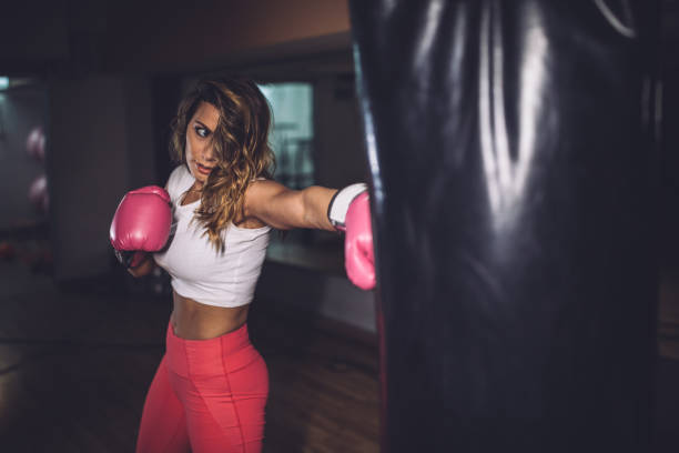 istock Beautiful lady boxer punching a punching bag 1130688544