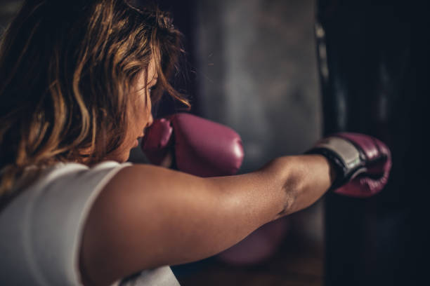 istock Young lady boxer punching a punching bag 1130688615