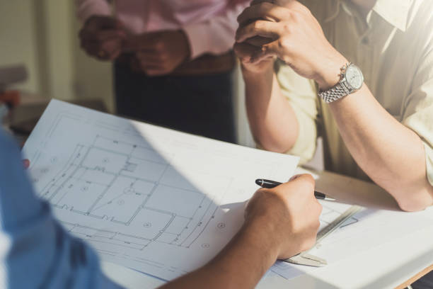 istock Group of architects discussing with blueprints plans in office design. Construction and structure concept. 1130689125