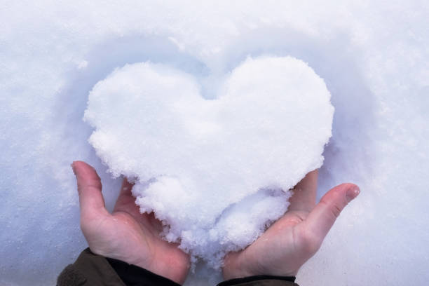 istock Man is holding a white heart from the snow in hands 1130689775