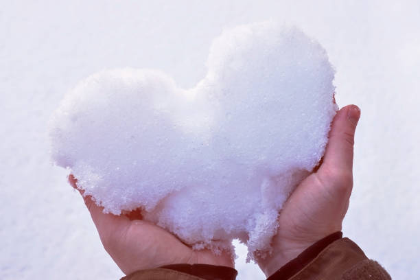 istock Man is holding a white heart from the snow in hands 1130689788