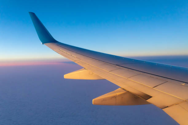 Wing of the plane in the dark blue sky on top of the gray clouds.