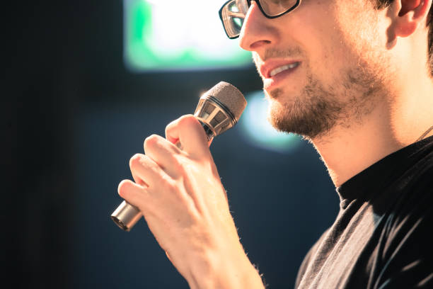 istock Speaker on the stage: Young Caucasian man is talking into a mirophone 1130693100
