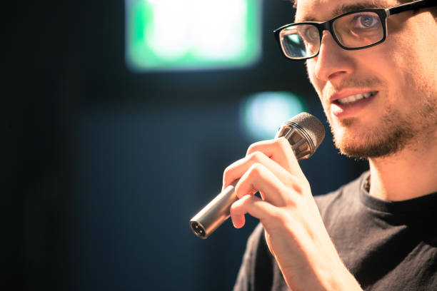 istock Speaker on the stage: Young Caucasian man is talking into a mirophone 1130693121