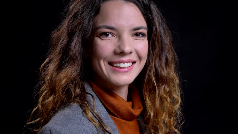 Closeup portrait of positive and confident young female looking at camera and smiling happily.