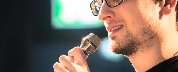 istock Speaker on the stage: Young Caucasian man is talking into a mirophone 1130693127
