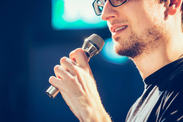 istock Speaker on the stage: Young Caucasian man is talking into a mirophone 1130693136