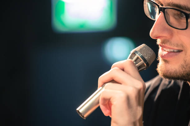 istock Speaker on the stage: Young Caucasian man is talking into a mirophone 1130693157