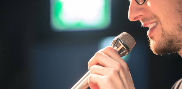 istock Speaker on the stage: Young Caucasian man is talking into a mirophone 1130693159