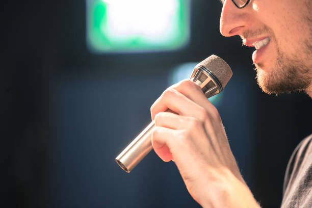 istock Speaker on the stage: Young Caucasian man is talking into a mirophone 1130693162