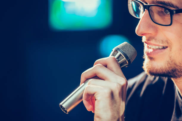 istock Speaker on the stage: Young Caucasian man is talking into a mirophone 1130693172
