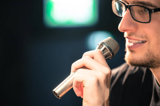 istock Speaker on the stage: Young Caucasian man is talking into a mirophone 1130693179