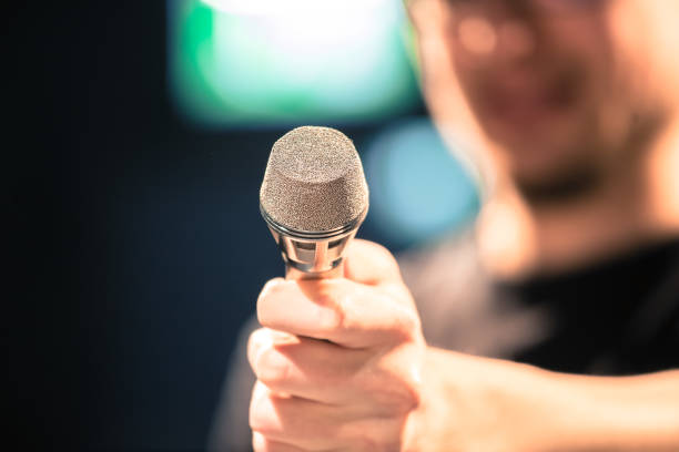 istock Speaker on the stage: Young Caucasian man is talking into a mirophone 1130693180