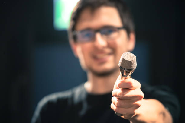 istock Speaker on the stage: Young Caucasian man is talking into a mirophone 1130693188