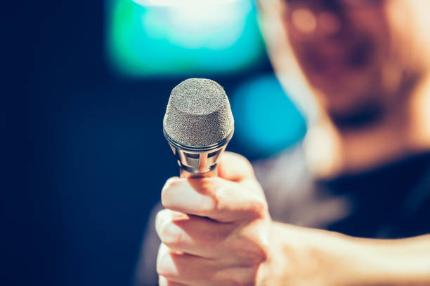 istock Speaker on the stage: Young Caucasian man is talking into a mirophone 1130693200
