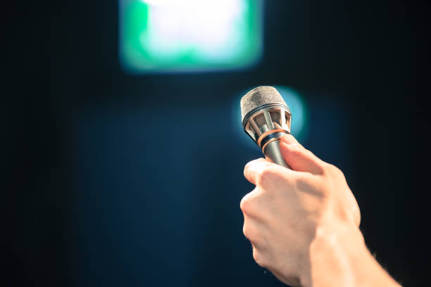 istock Speaker on the stage: Young Caucasian man is talking into a mirophone 1130693204