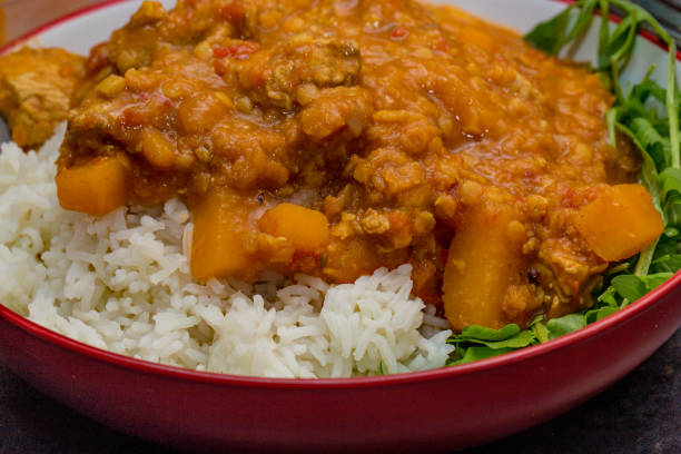 istock Authentic chicken dhal curry on a bed of white basmati rice with a green rocket salad 1130696007