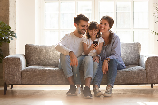 Familia feliz y niño divirtiéndose con smartphone en casa photo