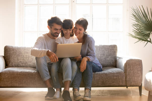 happy family with kid using laptop together on sofa - video call imagens e fotografias de stock