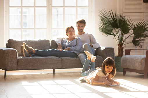 Padres felices relajándose en el sofá mientras el niño dibuja en el piso photo