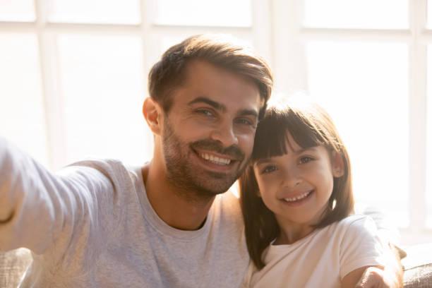 istock Dad and kid daughter with happy faces posing taking selfie 1130696705