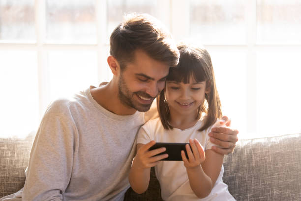 istock Happy dad and little child girl holding phone using smartphone 1130696708