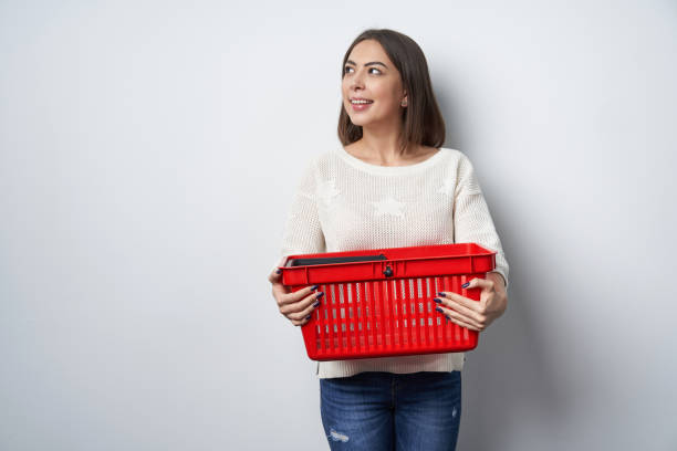 istock Woman holding empty shopping basket looking aside 1130699832