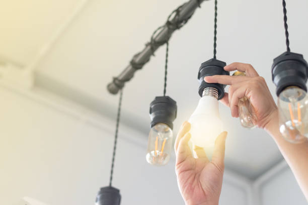 claro concepto de ahorro de energía led. asia hombre cambio bombillas de fluorescente compacto (cfl) con foco nuevo. - fotos de bombilla fotografías e imágenes de stock