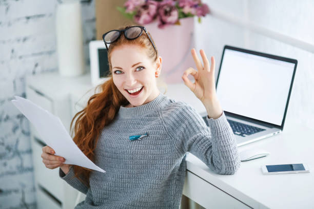 menina bem sucedida que trabalha no escritório. ela tem cabelo ruivo e um belo sorriso no rosto - business mobile phone telephone women - fotografias e filmes do acervo