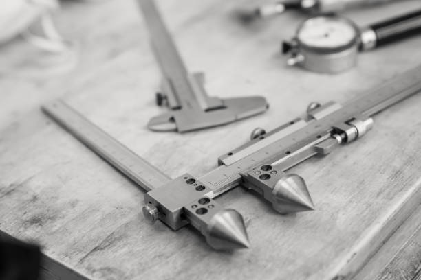 Metal measuring instruments on a wooden table. Product quality control. Black and white.