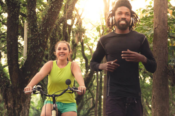 istock Woman Riding Bicycle With Man In Forest 1130701532