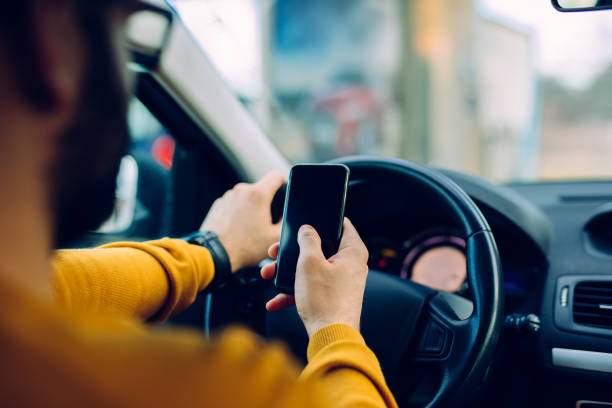 Business on wheels! Shot of a man using mobile phone while driving. Distracted stock pictures, royalty-free photos & images