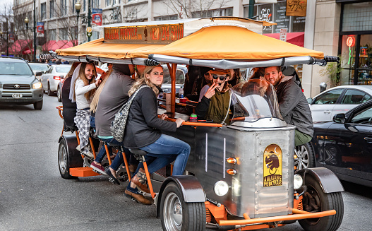 Asheville, NC, USA-2/16/19: A 13 seater pedal-powered touring vehicle transports tourists around town, with stops at pubs en route.