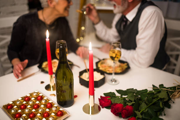 Senior couple having romantic dinner Happy mature couple having dinner with candles valentines day dinner stock pictures, royalty-free photos & images
