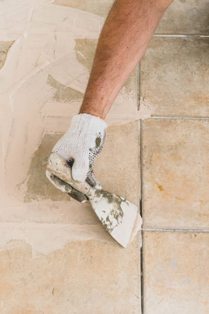 istock Man hand with trowel plastering a tiles, laying tiles.Construction concept. Selective focus 1130711975