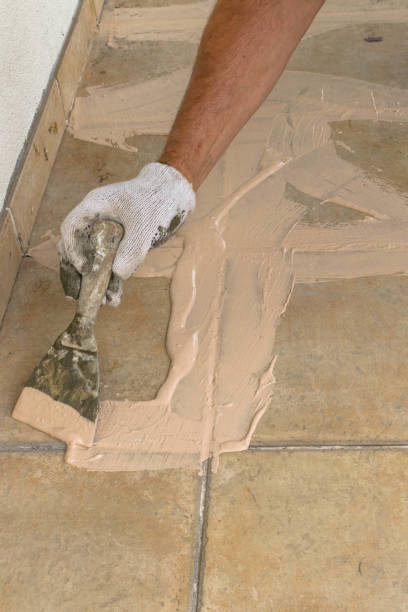 istock Man hand with trowel plastering a tiles, laying tiles.Construction concept. 1130712308