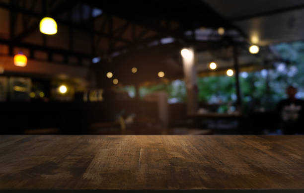 mesa de madera oscuro vacío delante de fondo abstracto borrosa bokeh del restaurante. puede ser utilizado para la exhibición o montaje de sus productos. simulacro para el espacio. - tienda fotos fotografías e imágenes de stock