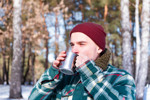 istock Male person drinks from a cup in a snowy winter forest. 1130716161