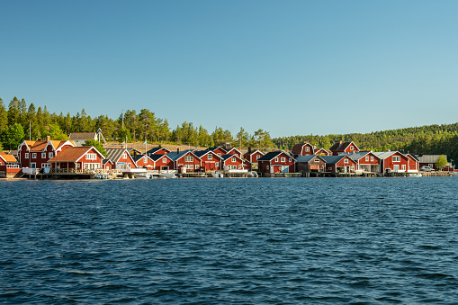 Beautiful summer view of a fishing camp on the Swedish north east coast. With small red buildings in a row near by the water, and sunshine and clear blue sky