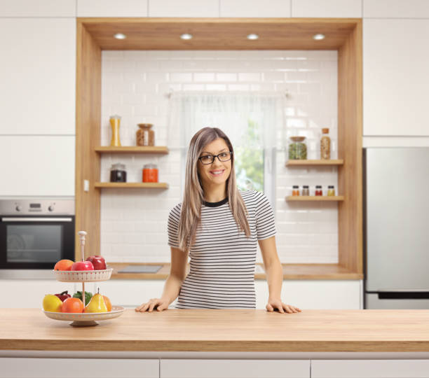 istock Smiling young woman standing behind a wooden worktop in a modern 1130721149