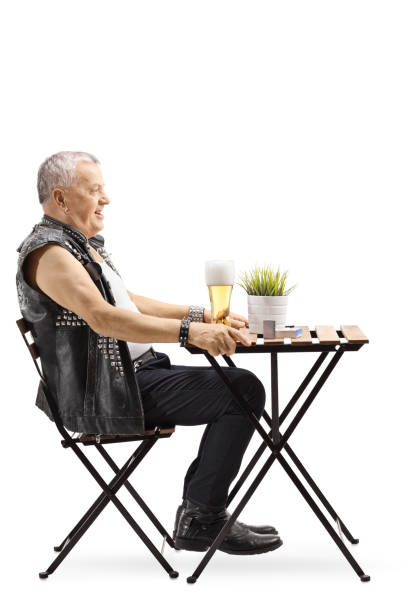 istock Old punk man sitting at a table and drinking beer 1130721295