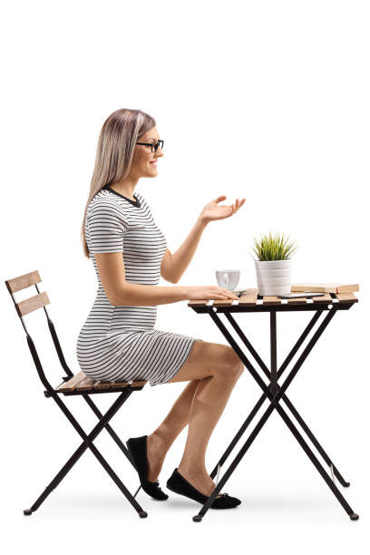 istock Young woman sitting at a table with coffee and gesturing with hand 1130723023