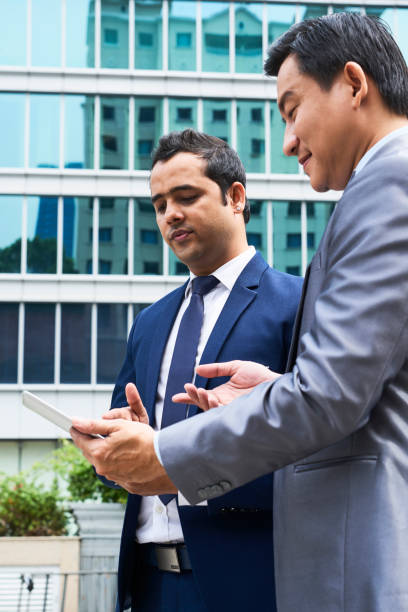 istock Businessmen using tablet pc outdoors 1130725795