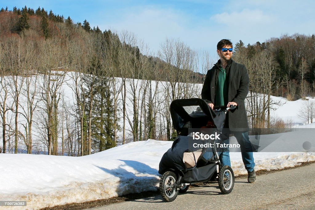 Father with stroller in the snow Father pushes strollers through landscape with snow. 2-3 Years Stock Photo