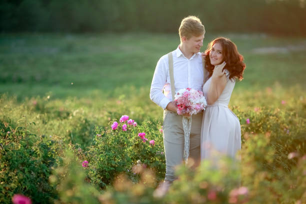 beautiful gorgeous bride and stylish handsome groom, rustic couple in a rose field beautiful gorgeous bride and stylish handsome groom, rustic couple in a rose field. suspenders wedding bride groom stock pictures, royalty-free photos & images