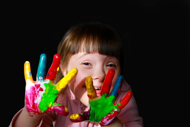söt liten unge med målade händer isolerade på den svarta - downs syndrome work bildbanksfoton och bilder