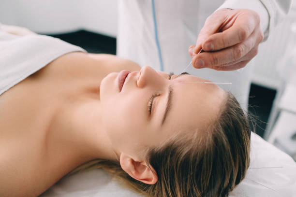 istock Acupuncturist inserting a needle into a female face 1130730033