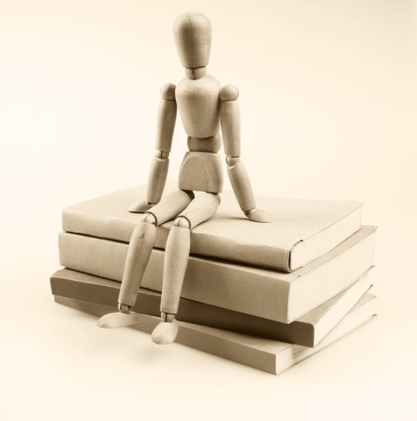 figura de madera muñeca sentada en la pila de libros. - mannequin book education doll fotografías e imágenes de stock