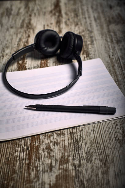 istock Composition of black headphones next to an empty pentagram notebook 1130731510